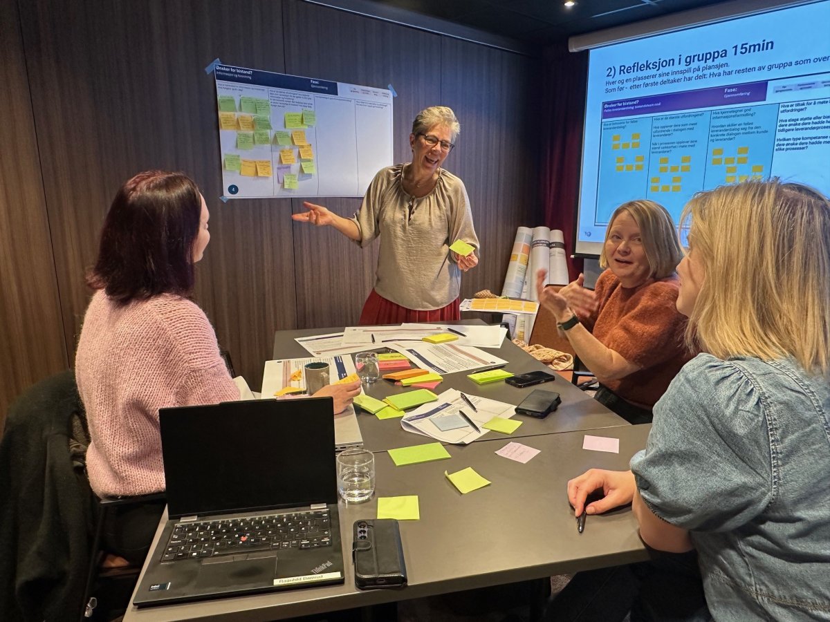 Kvinner sitter rundt et bord med lapper og pc