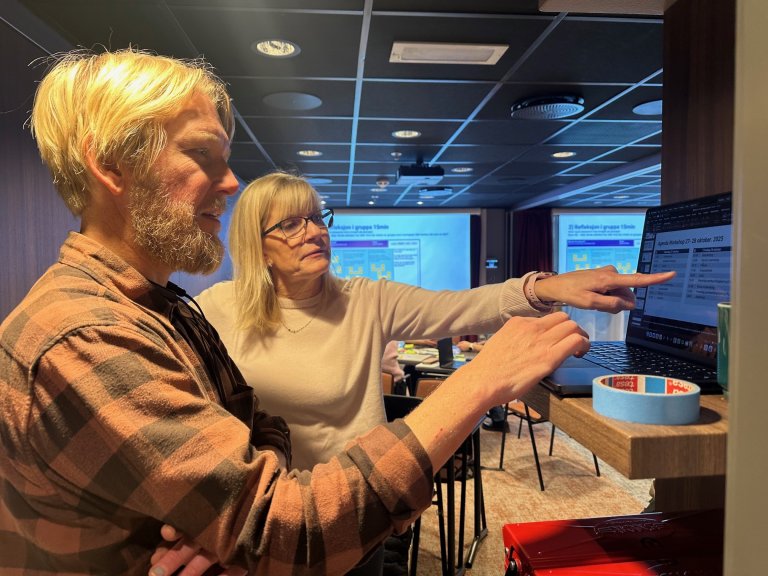 Mann og kvinne foran en pc, peker på skjermen