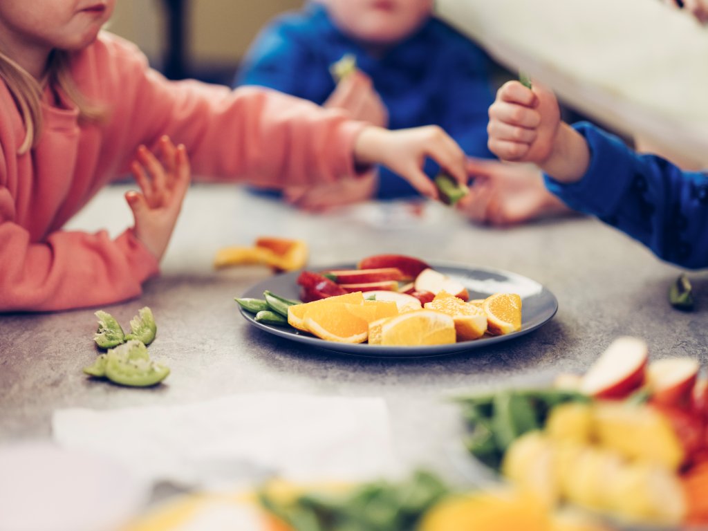 Barn forsyner seg av et fat med frukt