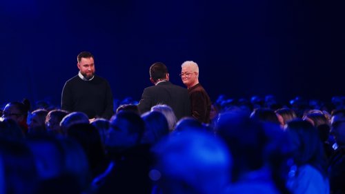 3 foredragsholdere på scenen med publikum i forgrunden på konferansen