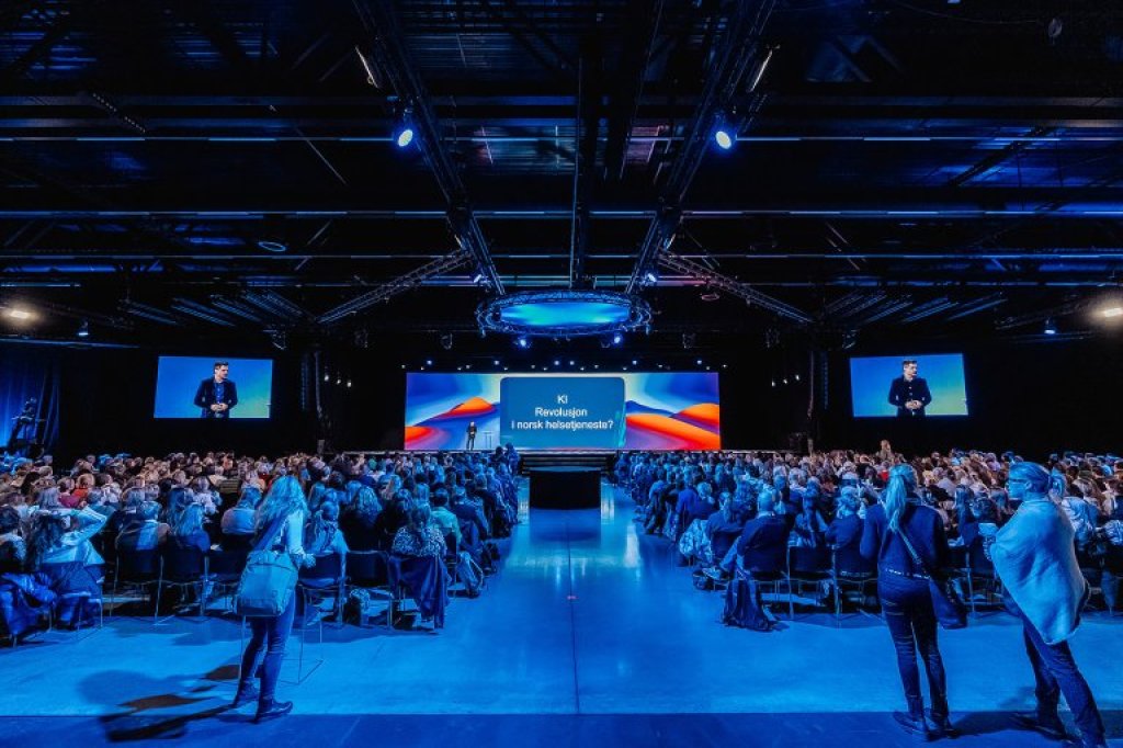 Menneskemengde som sitter i konferansehall