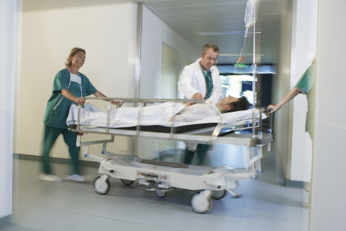 Leger frakter en pasient i en sykeseng gjennom gangene på et sykehus.
