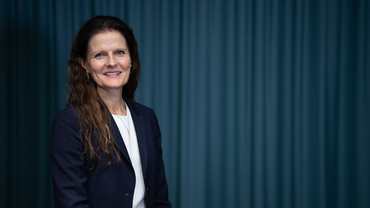 Smilende kvinne  med langt hår i dressjakke