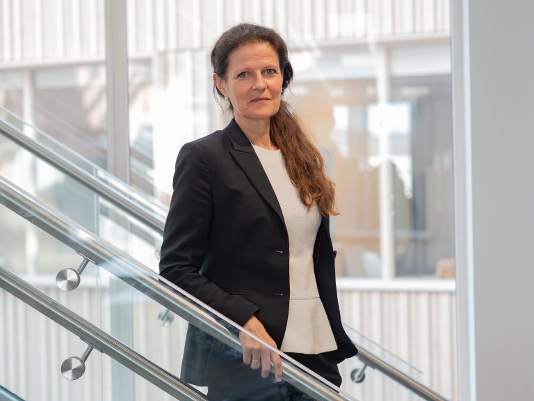 kvinne med langt hår og dress i trapp