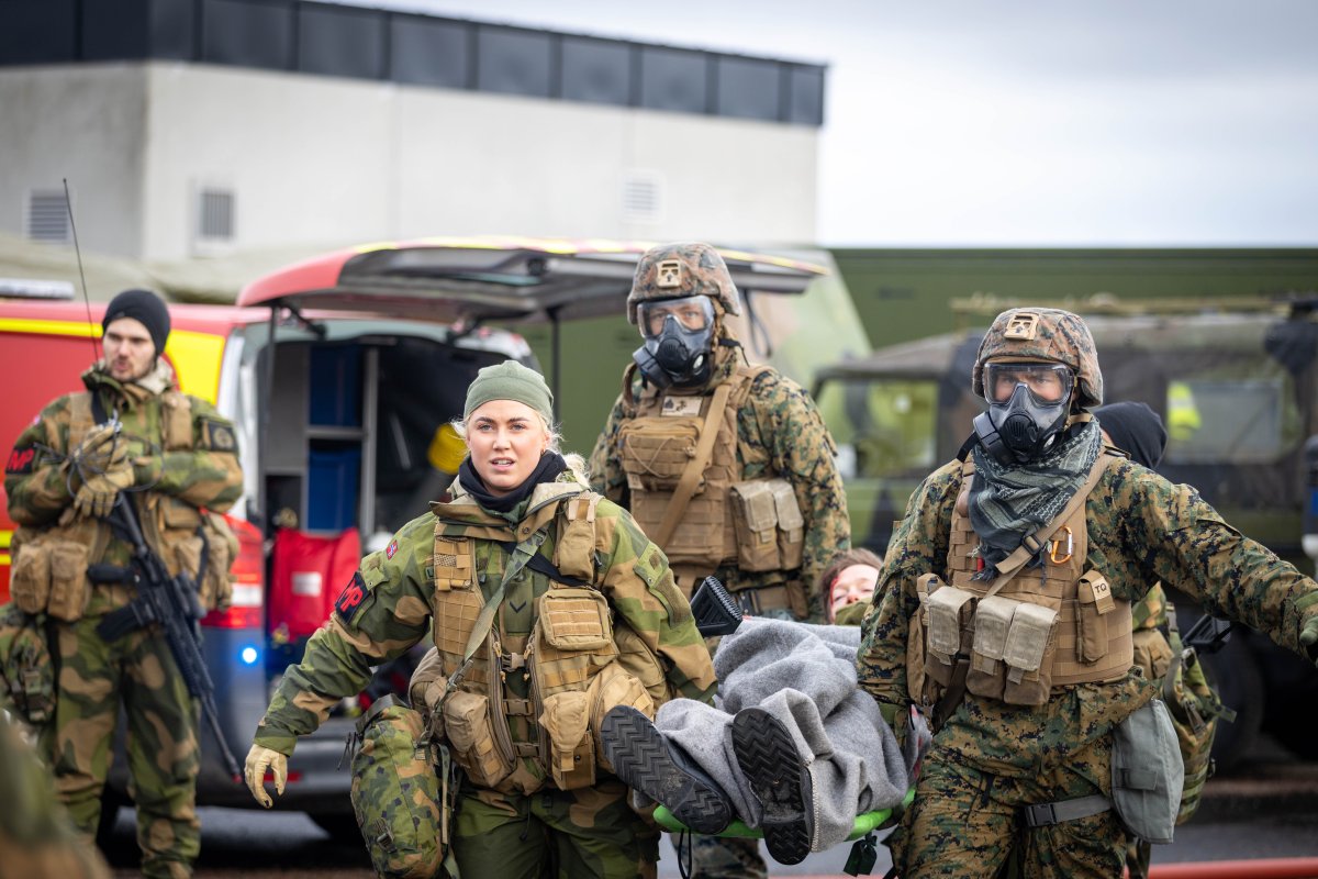 Bilde av kvinelige og mannlige soldater som bærer en båre med en skadet person.