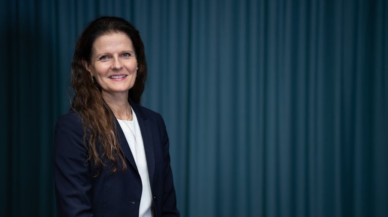 Smilende kvinne i blå jakke og hvit skjorte