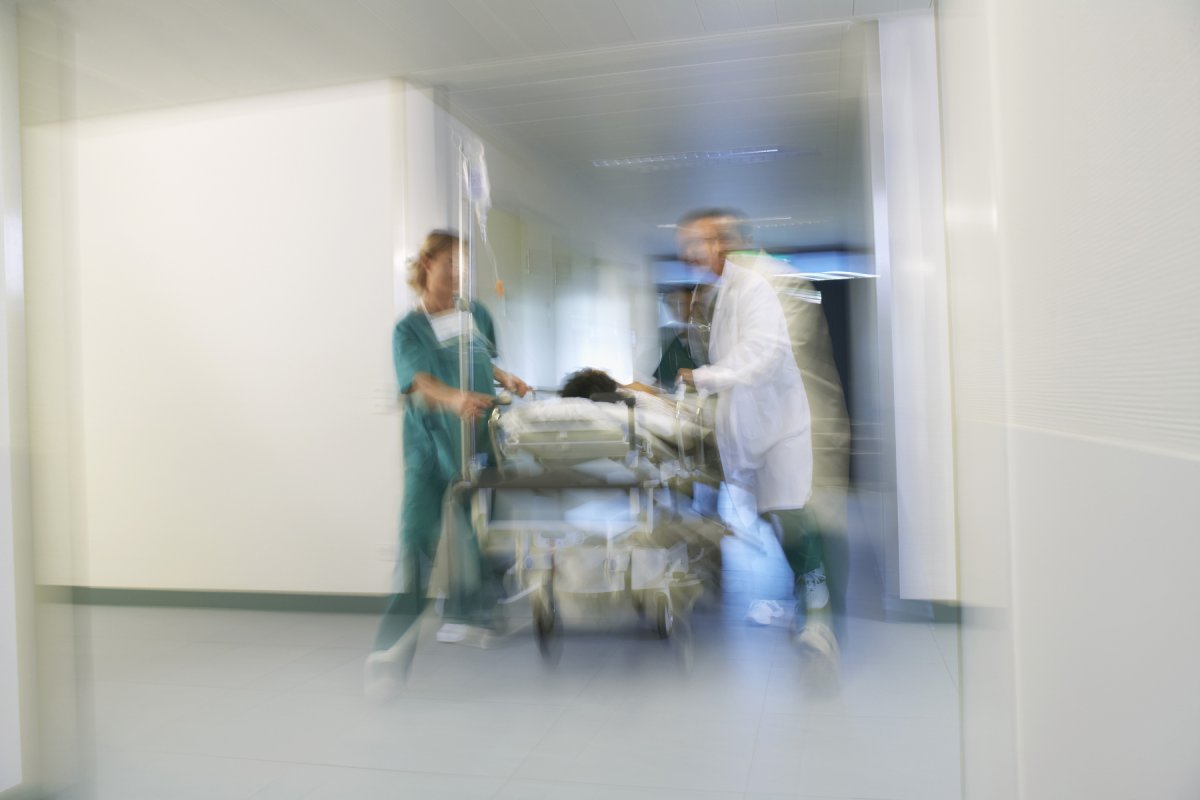 Diffust bilde av pasient i sykeseng som trilles inn på sykehus av leger.