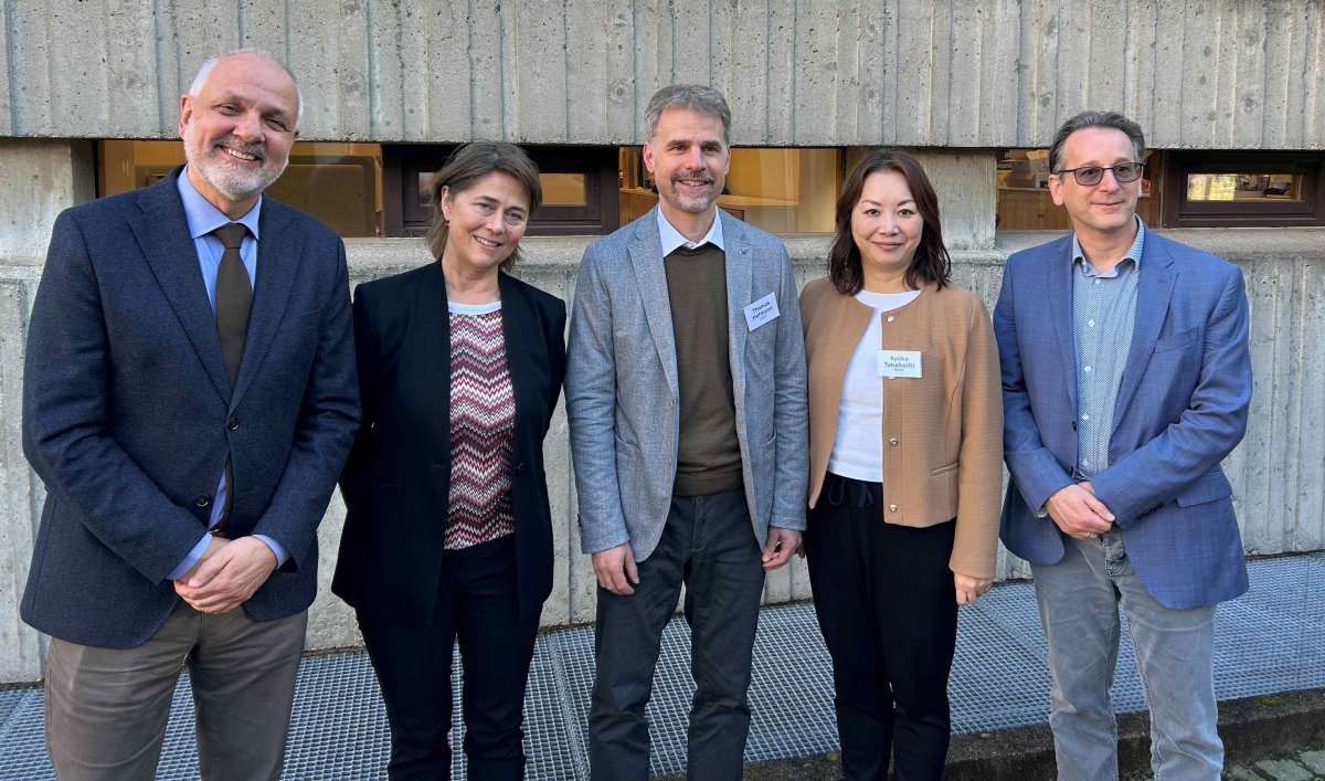 Tre menn og to kvinner står ved siden av hverandre foran en vegg