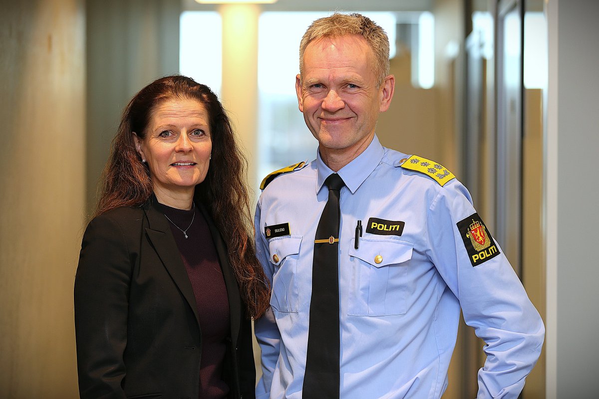 Kvinne i dressjakke og mann i politiuniform 