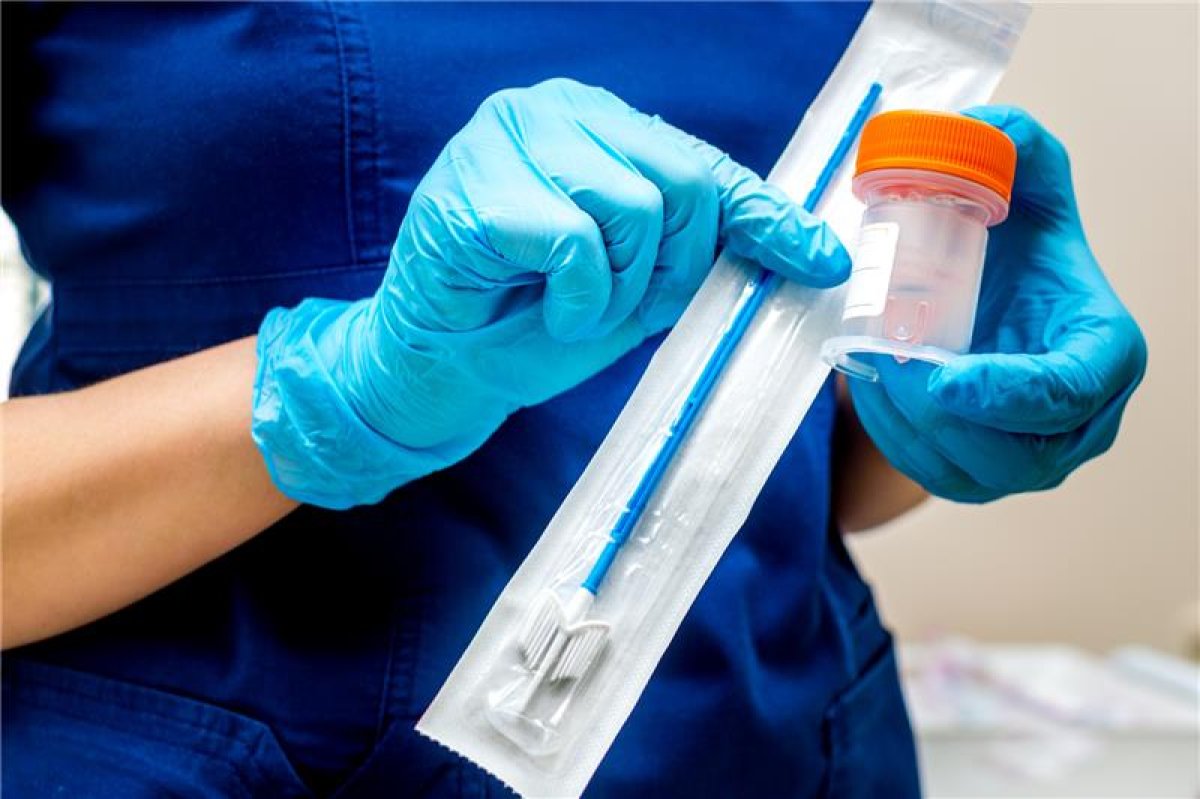 Helsepersonell med hansker holder i en HPV test