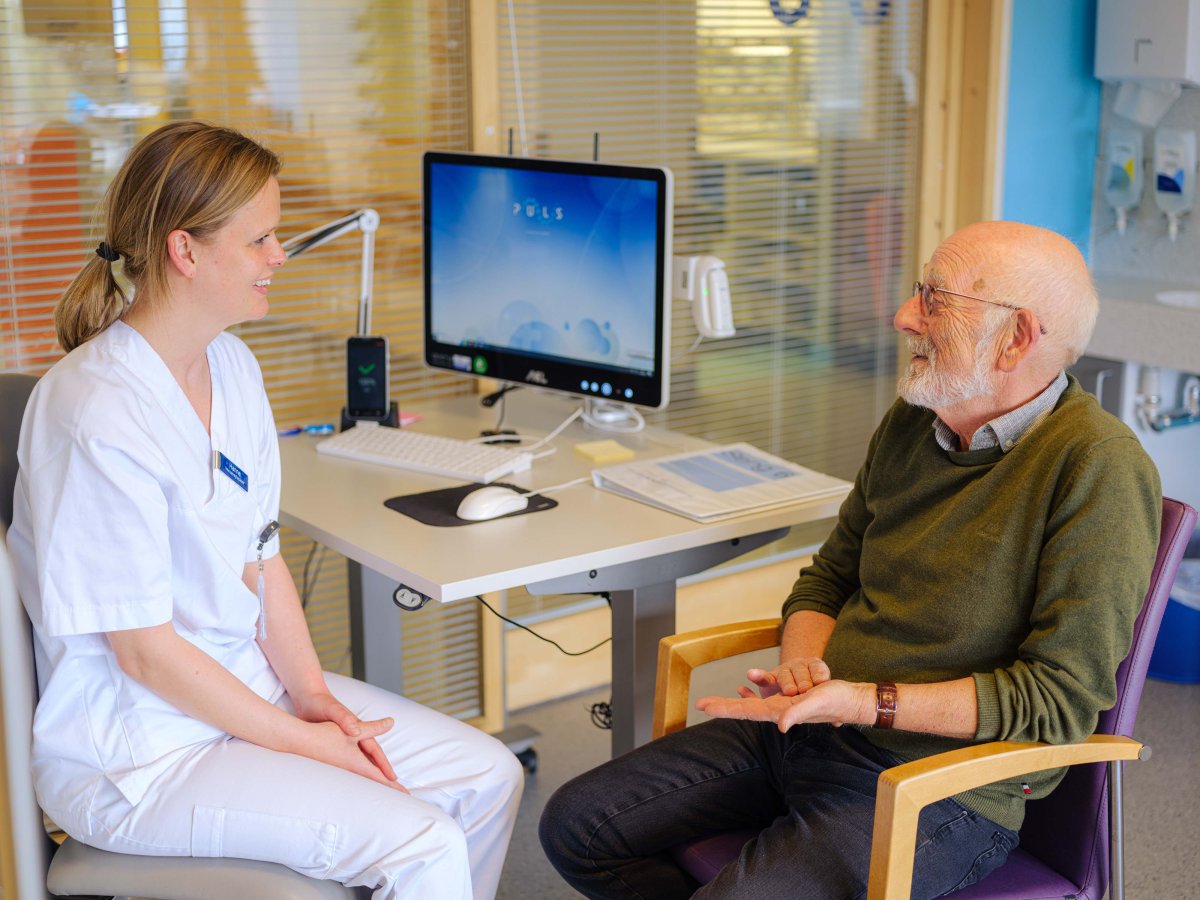 Helsepersonell sitter sammen med gammel mann
