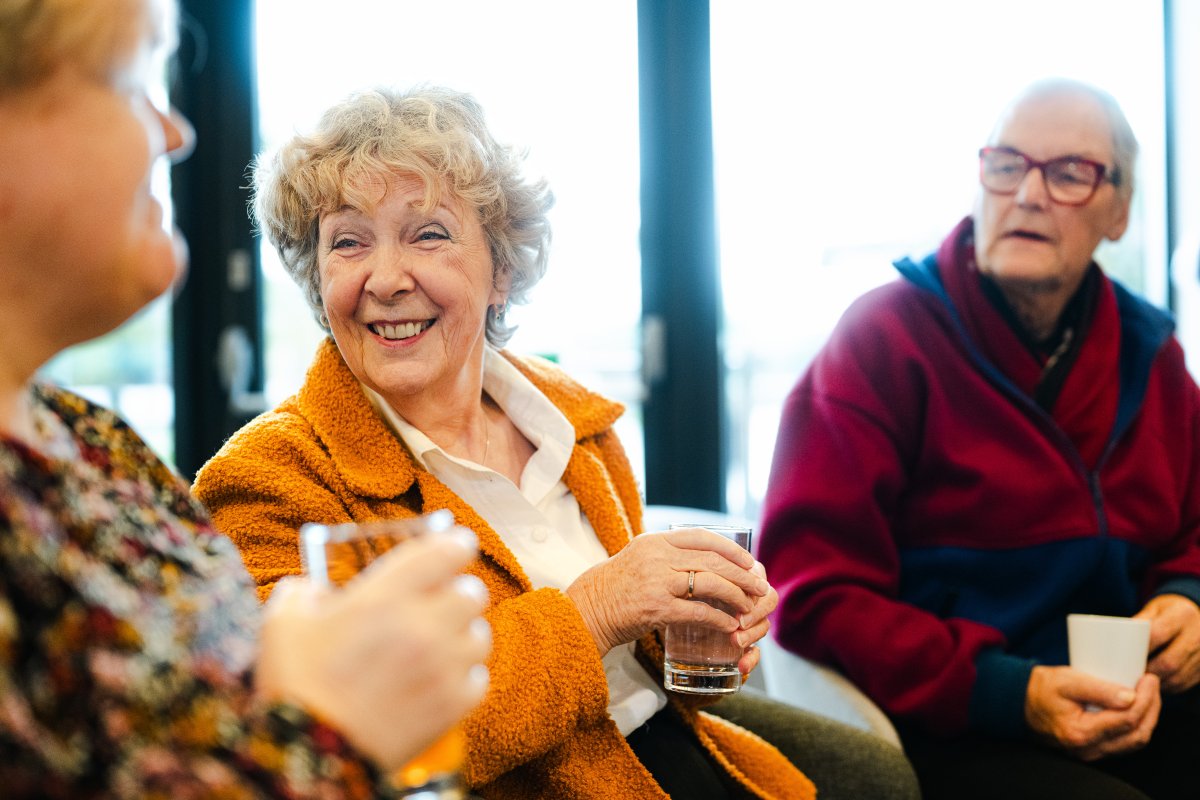 Tre eldre mennesker smiler sammen