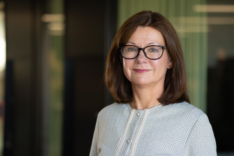 Smilende kvinne med mørkt langt hår og briller