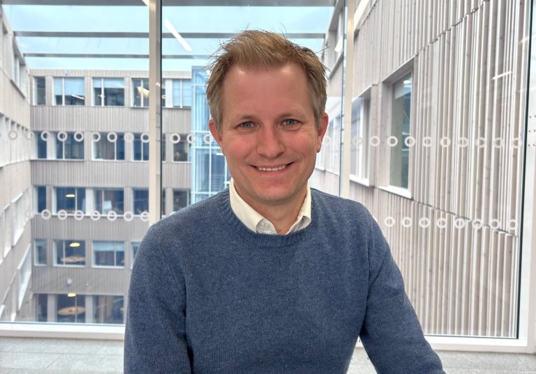 Smilende mann sittende foran vindu